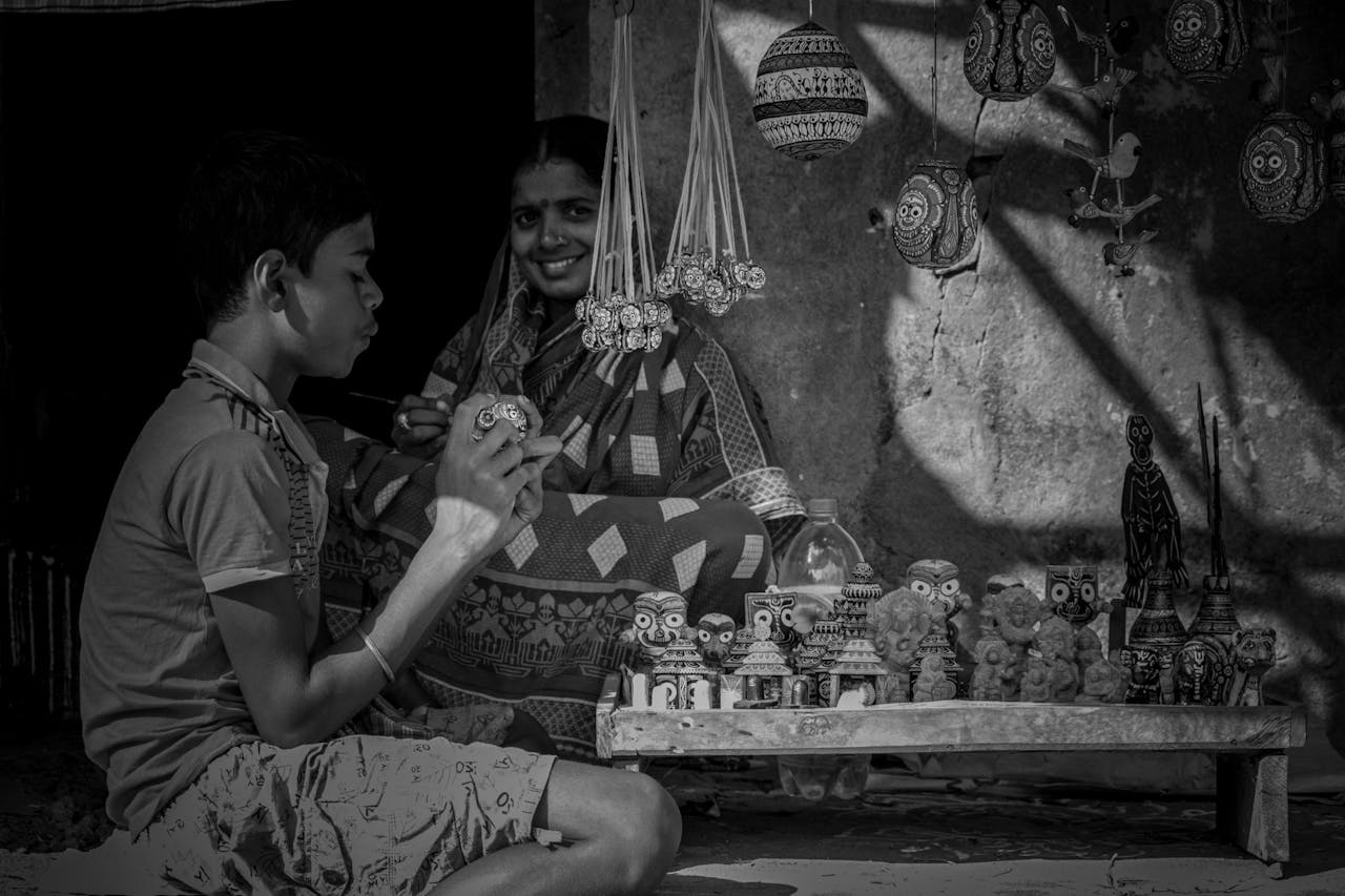 A black and white photo capturing Indian artisans with handmade pottery and ceramics.