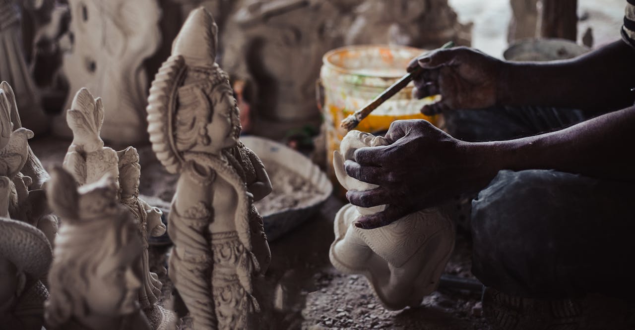 services-03 Close-up of artisan crafting a detailed Buddha figurine in a workshop, showcasing intricate artistry.