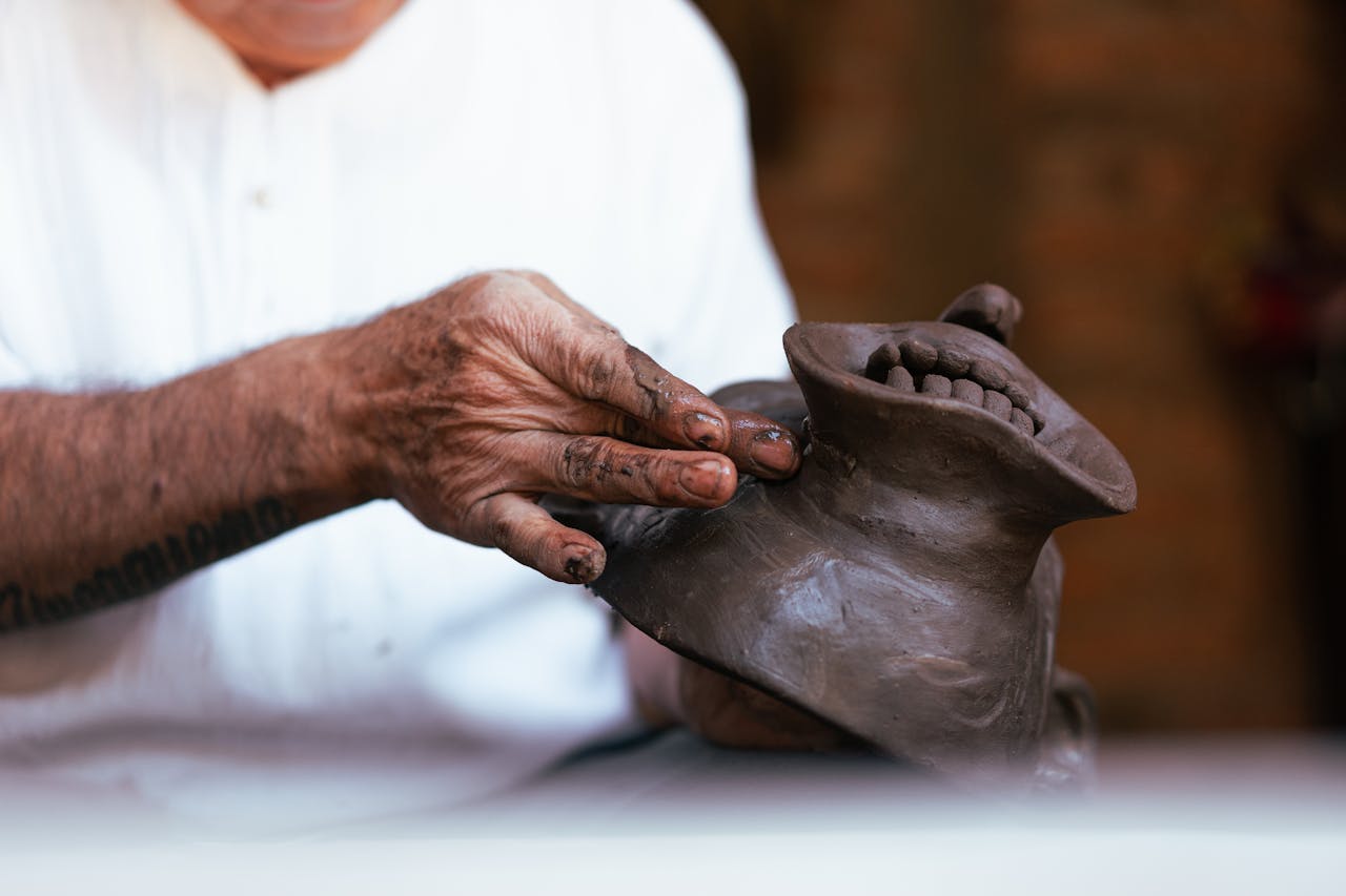 services-02 Close-up of a skilled artisan crafting a clay mask with precise hand movements in a workshop.